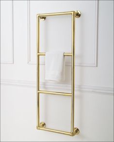 a gold towel rack with two towels hanging from it's sides, against a white wall