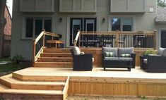 a deck with chairs and couches in front of a house