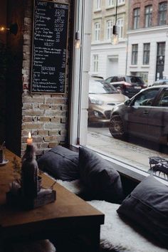 a window with a chalkboard on the wall next to pillows and a candle in front of it