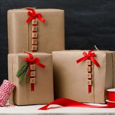 three presents wrapped in brown paper and tied with red ribbon are sitting on a table