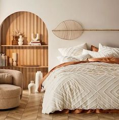 a large bed sitting next to a chair and book shelf in a bedroom on top of a hard wood floor