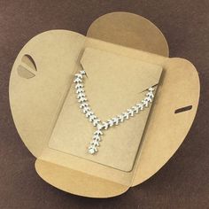 an open cardboard box with a necklace in the shape of a heart on top of it