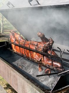 a large piece of meat is cooking on an outdoor grill