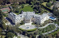 an aerial view of a mansion with tennis courts