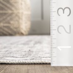 a measuring ruler on the floor next to a white rug and pillow in a living room