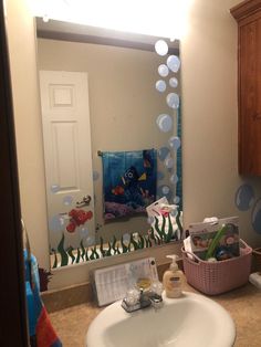 a bathroom sink with soap, toothbrushes and lotion on it in front of a mirror