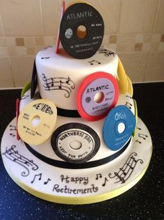 a three tiered cake with music themed decorations on the top and bottom, along with cd's