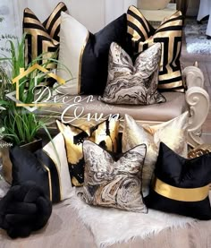 black and gold pillows are sitting on the floor in front of a potted plant