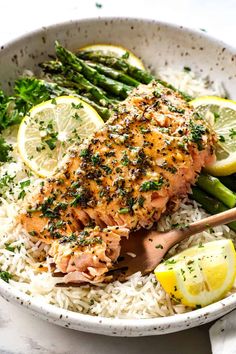 salmon and asparagus on rice in a bowl with lemon wedges