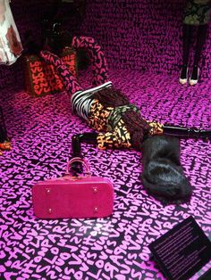 a pink suitcase sitting on top of a purple and black floor next to other items