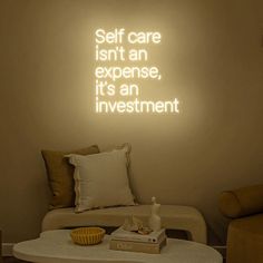 a living room filled with furniture and a neon sign on the wall above it that says self care isn't an expensive, it's an investment