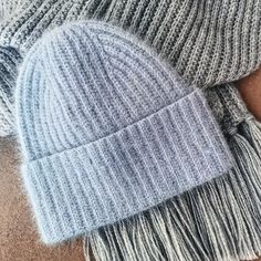 two hats with tassels on top of each other, one is grey and the other is white