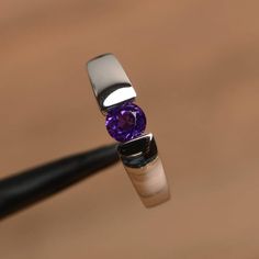 It is a natural amethyst ring. The main stone is 5 mm*5 mm round cut.weight about 0.48 carats.The basic metal is sterling silver and plated with rhodium.To change the metal to a solid gold (white/rose) or platinum is also available, please ask for a quotation if you want.You can also go to my shop Home for more elegant rings: https://www.etsy.com/shop/godjewelry?ref=hdr_shop_menu Amethyst is February birthstoneMore amethyst rings:https://www.etsy.com/shop/godjewelry?ref=seller-platform-mcnav&sec White Gold Birthstone Ring With Tension Setting, Classic Amethyst Round Cut Birthstone Ring, Modern Round Birthstone Promise Ring, Classic Amethyst Birthstone Ring With Round Cut, Modern White Gold Amethyst Ring, White Gold Amethyst Ring Round Cut, White Gold Amethyst Ring With Round Cut, Amethyst Birthstone Ring In White Gold, Amethyst Promise Ring With Round Cut