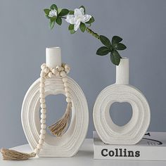 two white vases sitting on top of a table next to each other with flowers in them