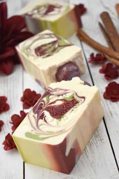 two soap bars sitting next to each other on top of a white wooden table with red flowers