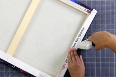 a person is making a frame out of cardboard and fabric with scissors on the table