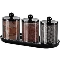 three canisters with lids are sitting on a tray, each containing different types of food