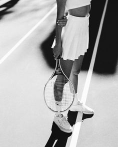 a woman holding a tennis racquet on top of a tennis court next to a car