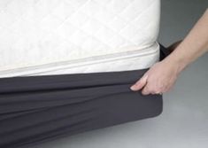 a person holding onto the bottom of a mattress