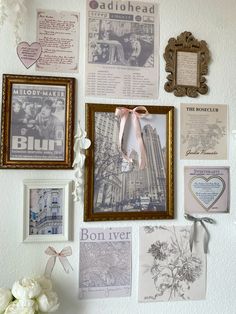 a wall covered in pictures and photos with flowers next to it, including an old fashioned frame