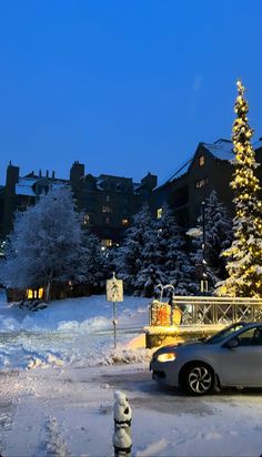 a car parked in front of a christmas tree on the side of a road covered in snow