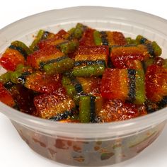 a plastic container filled with cooked vegetables on top of a white tablecloth covered table