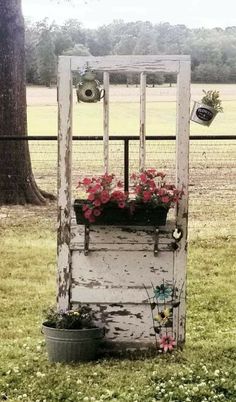 an old door with flowers in it is sitting on the grass