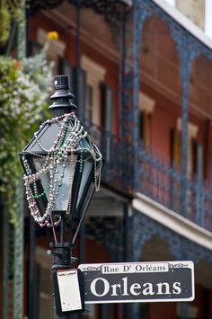 a street sign with beads hanging from it's side on a lamp post in front of a building