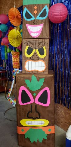 three cardboard tiki masks are stacked on top of each other in front of decorations