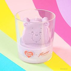 a glass cup with a small plastic animal in it's mouth on a multi - colored background