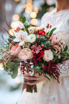 a woman holding a bouquet of flowers and greenery in front of a christmas tree