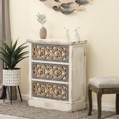 a white dresser sitting next to a window with a clock on the wall above it