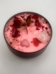 a bowl filled with ice and flowers on top of a white table next to a spoon