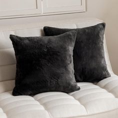 two black pillows sitting on top of a white couch