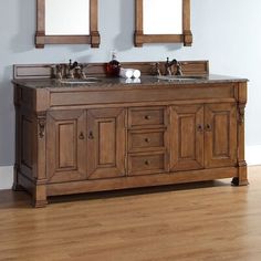 a bathroom vanity with two mirrors above it and wood floors in front of the sink