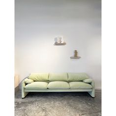 a green couch sitting in front of a white wall