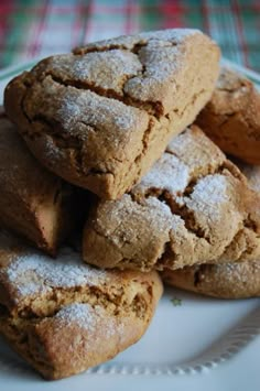 a pile of cookies sitting on top of a white plate covered in powdered sugar