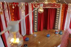 a circus themed birthday party with balloons and lights on the walls, red curtained drapes, and decorations