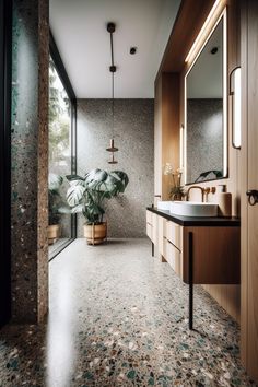 a bathroom with a sink, mirror and plant in it