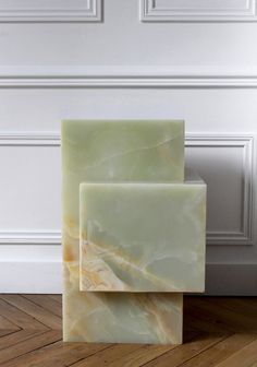 two blocks of soap sitting on top of a wooden floor in front of a white wall