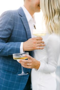 a man and woman kissing while holding wine glasses