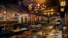 an empty restaurant with wooden tables, chairs and lights hanging from the ceiling above them