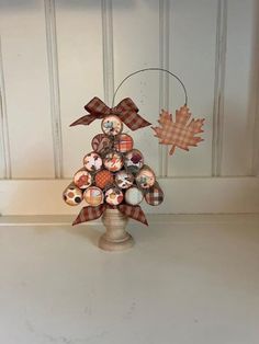 a small christmas tree made out of buttons and plaid ribbon on top of a white table