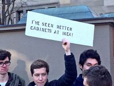 a group of young men holding up a sign that says i've seen better cabinets at ikea