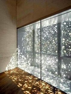 shadows cast on the wall and floor in front of a glass window with white circles