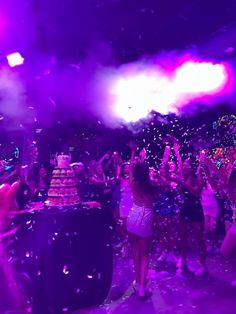 people are throwing confetti on the dance floor at a birthday party with purple lighting