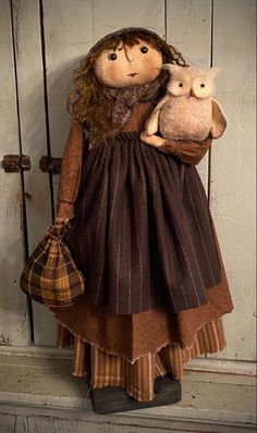 a doll is holding an owl in her arms while standing next to a wooden door