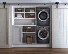 a washer and dryer sitting in a room next to some shelves with baskets