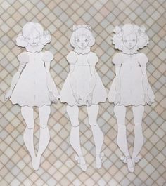 three paper cutouts of girls in white dresses on a tile background with checkered wallpaper