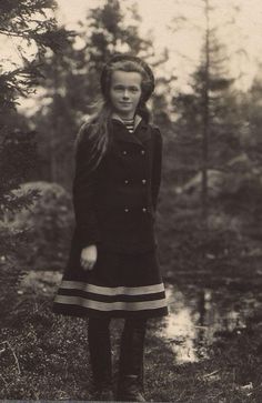 an old black and white photo of a woman in the woods